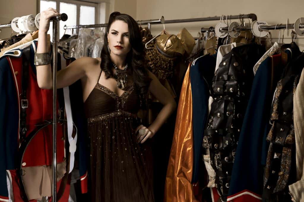 Fashion model standing between clothes racks.